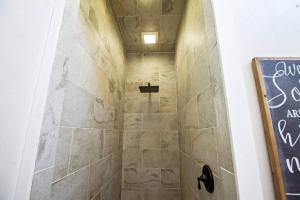 W łazience z wyłożoną kafelkami ścianą znajduje się prysznic. w obiekcie Belle âme w mieście Smithville
