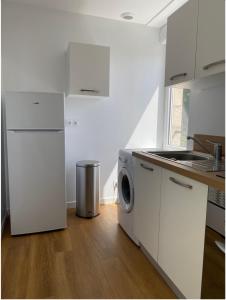 uma cozinha com armários brancos e uma máquina de lavar e secar roupa em Lorient: appartement élégant em Lorient