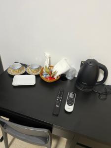 uma mesa com uma cafeteira e dois pratos e um controlo remoto em Alì Babà Rooms em La Spezia