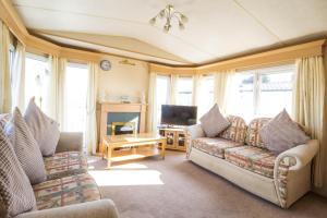a living room with two couches and a television at 6 Berth Caravan For Hire With Sea Views At Haven Seashore Ref 22087a in Great Yarmouth