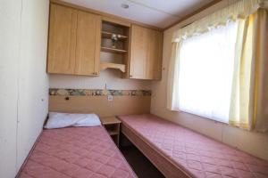 um pequeno quarto com um banco rosa e uma janela em 6 Berth Caravan For Hire With Sea Views At Haven Seashore Ref 22087a em Great Yarmouth