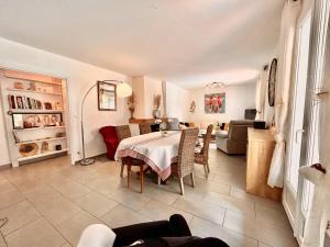 a dining room with a table and a living room at Villa 110m2, 7 pers, Jacuzzi , 3 chambres, terrain clos et arboré 2500m2 in Trèbes