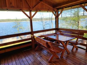 a wooden porch with a table and chairs on a lake at Siedlisko nr 2 nad jeziorem Skarlińskim, jezioro, mazury, domki letniskowe in Kurzętnik