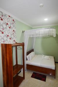 a small bedroom with a bed with a curtain and a table at BETTER LIFE HOTEL KASULU 