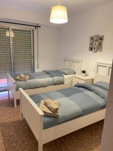 een slaapkamer met 2 bedden en een raam met een lamp bij UIM Mediterraneo Isabel 23 Wifi in Puerto de Sagunto