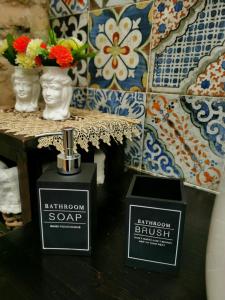 a bottle of bathroom soap on a table with flowers at Home Kitó Ortigia in Siracusa