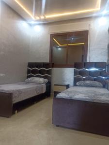 a bedroom with two beds and a mirror at Bel appartement in Chefchaouene