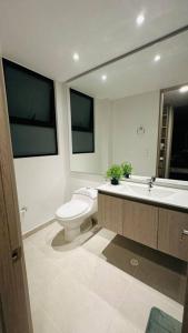 ein Badezimmer mit einem WC, einem Waschbecken und einem Spiegel in der Unterkunft Brand new Apt, perfect City view in Bogotá