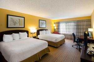 a hotel room with two beds and a desk at Sonesta Select Dallas Richardson in Richardson