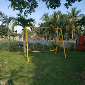 a yellow swing set in a yard with palm trees at Villa Cecilia in Guerra