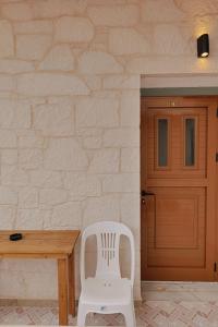 a white chair next to a wooden table and a door at Villa Abedini in Ksamil