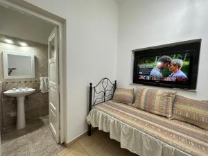 a bathroom with a couch and a tv on the wall at AMPLIOS Departamentos PASAJE TUCUMÁN in Alta Gracia
