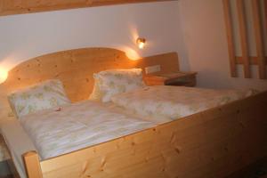 ein Holzbett mit einem Kopfteil aus Holz im Schlafzimmer in der Unterkunft Ferienwohnung Mützengruß in Filzmoos