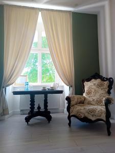 ein Zimmer mit einem Tisch und einem Stuhl vor einem Fenster in der Unterkunft Pałac Chichy 