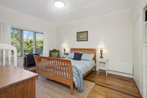 a bedroom with a bed and a desk and window at Gowan Ross Cottage in Mount Wilson