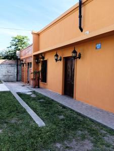 un edificio naranja con una puerta y un patio de césped en Casa quinta LA ESPERADA en Reconquista