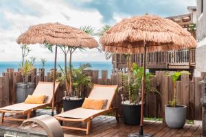 un groupe de chaises et de parasols sur une terrasse dans l'établissement Lilie location manapany 4 étoiles, à Petite Île
