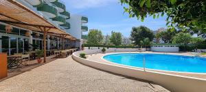 a large swimming pool in front of a building at Apartamento da Avó Té - em frente à Praia c piscina in Portimão