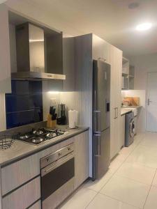 a kitchen with a stove and a refrigerator at Cosy & lovely stylish apartment in Rosebank in Johannesburg