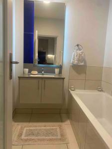 a bathroom with a tub and a sink and a mirror at Cosy & lovely stylish apartment in Rosebank in Johannesburg