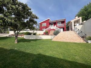 una casa roja con escaleras y un árbol en un patio en Casa Rural Senda de los Lobos, en Uclés