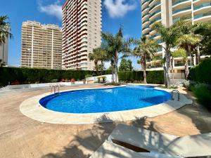 een groot zwembad met palmbomen en gebouwen bij Esmeralda Suites 21º piso in Calpe
