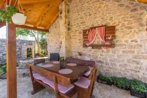 una mesa de madera y sillas en una habitación con una pared de piedra en Peaceful house in nature nearby National Park Krka, en Brištane