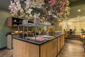 una panadería con una barra con pasteles y flores en Leonardo Hotel Antwerpen, en Amberes