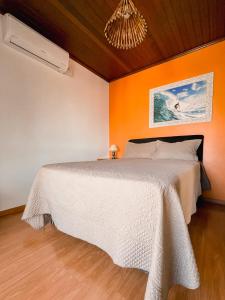 a bedroom with a white bed with an orange wall at Casa da bela Vista in Gramado