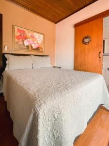a bedroom with a white bed in a room at Casa da bela Vista in Gramado