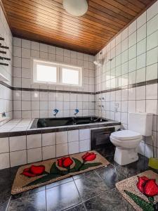 uma casa de banho com WC e flores vermelhas no chão em Casa da bela Vista em Gramado