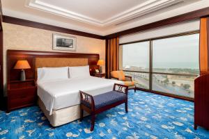 クウェートにあるホリデイイン クウェートのベッドと大きな窓が備わるホテルルームです。