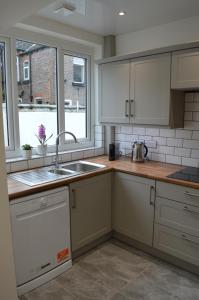 uma cozinha com armários brancos, um lavatório e uma janela em Library House em Liverpool