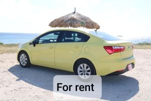 un pequeño coche amarillo estacionado en la playa con una sombrilla en The Santy's, en Oranjestad