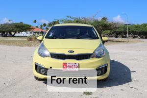 a small yellow car parked in a parking lot at The Santy's in Oranjestad