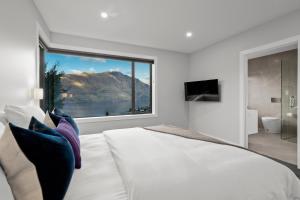 ein Schlafzimmer mit einem großen Bett und einem großen Fenster in der Unterkunft Rivendell, Luxury Cliff Top Home, Queenstown - Spa & Sauna in Queenstown