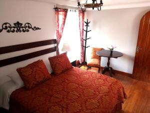 1 dormitorio con 1 cama con edredón rojo y ventana en Kori Gems Inn, en Cusco