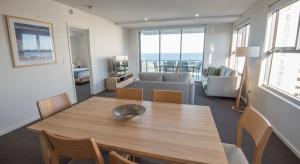 a dining room with a table and a living room at Verve on Cotton Tree in Maroochydore