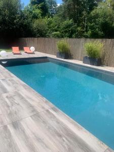 una piscina con 2 sillas en un patio en Villa avec piscine aux portes du circuit des 24 heures, en Arnage