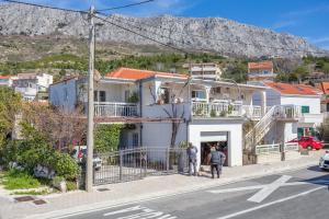 twee mensen die door een straat lopen voor een huis bij Apartments by the sea Orij, Omis - 7534 in Dugi Rat