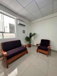 two couches sitting in a room with a window at Alojamiento increíble!! in Iquitos