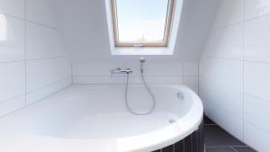 eine weiße Badewanne in einem Badezimmer mit Fenster in der Unterkunft Spacious 4 Bedroom Apartment near City Center in München