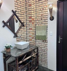 a bathroom with a sink and a brick wall at Recanto Vieira Praia do Estaleiro in Balneário Camboriú