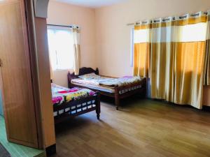 a room with two beds and a window at Belair cottages in Kotagiri