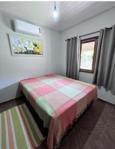 a bedroom with a bed with a quilt on it at Recanto Vieira Praia do Estaleiro in Balneário Camboriú