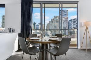 Broad Land Premium Apartments Chatswood Sydney في سيدني: غرفة طعام مع طاولة وكراسي ونافذة كبيرة