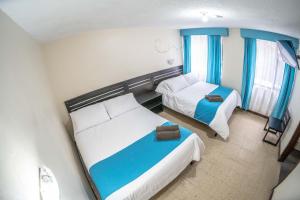 Habitación de hotel con 2 camas y cortinas azules en Hotel Tungurahua, en Baños