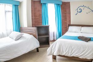 1 dormitorio con 2 camas y cortinas azules en Hotel Tungurahua, en Baños