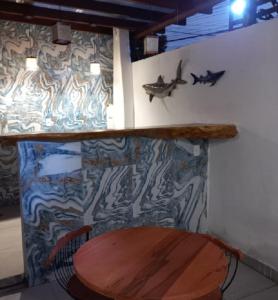 a room with a wooden table and a wall with a fish on it at Pousada Luz da Lua in Búzios