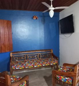 1 dormitorio con una pared azul, 1 cama y 2 sillas en Pousada Luz da Lua, en Búzios
